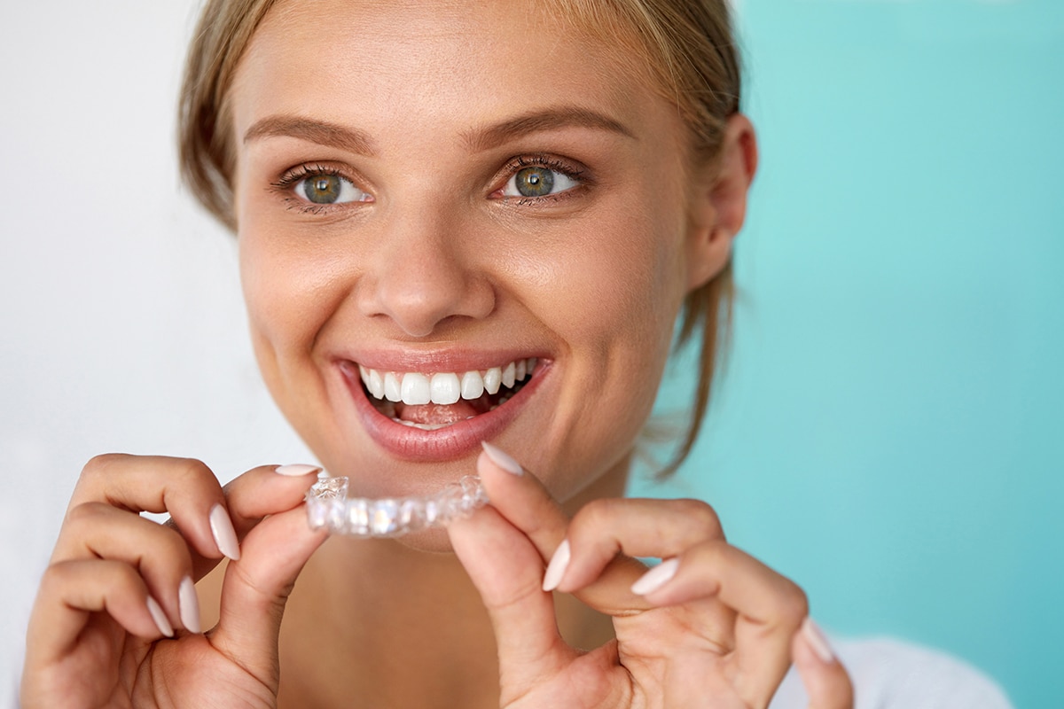 Teeth Whitening. Beautiful Smiling Woman With White Smile, Straight Teeth Using Teeth Whitening Tray. Girl Holding Invisible Braces, Teeth Trainer. Dental Treatment Concept. High Resolution Image