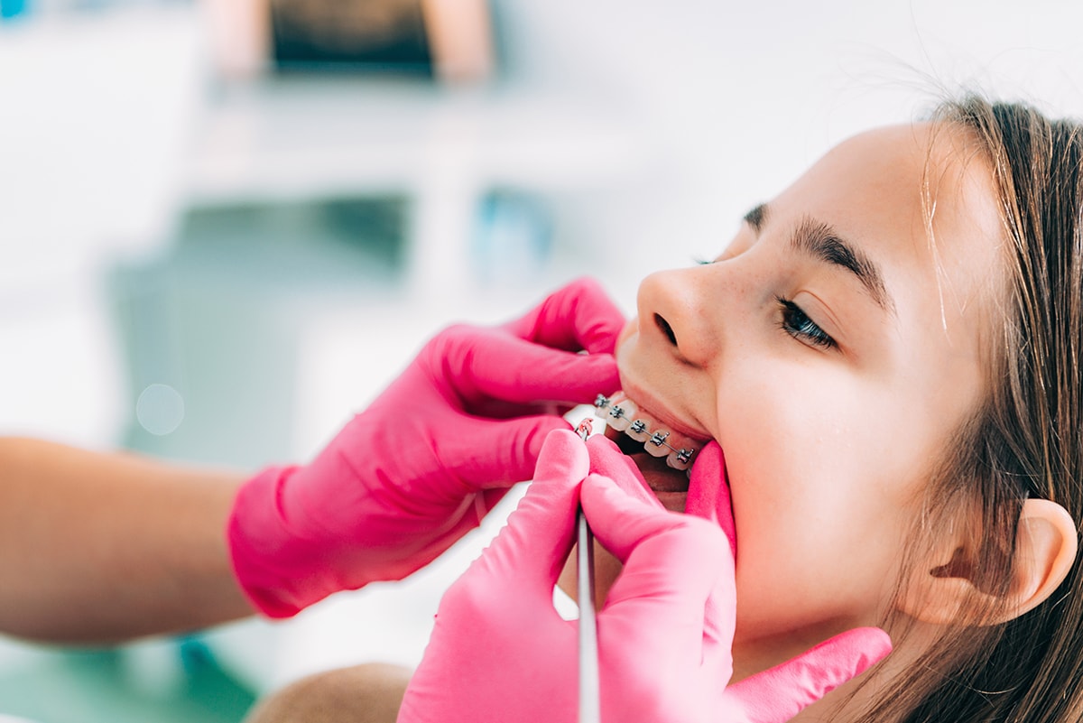 Orthodontist fixing girl’s dental braces