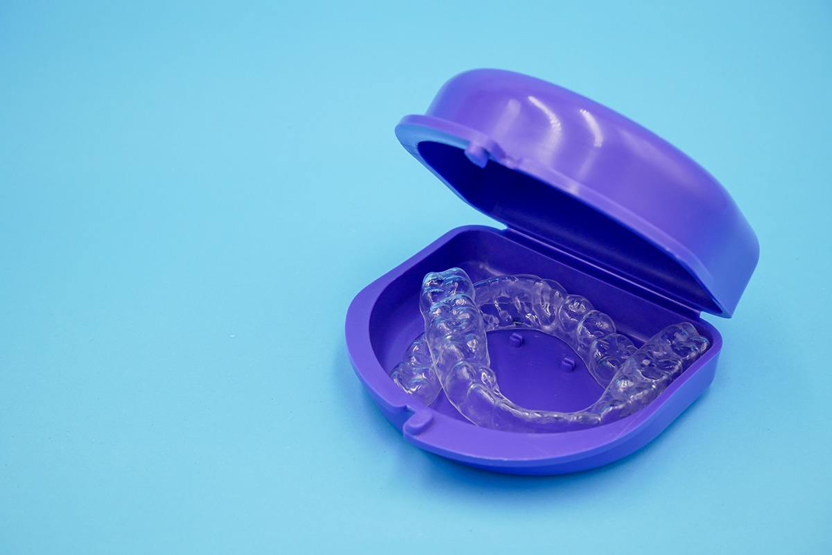Clear retainer in the purple box set that isolated on blue background clear plastic retainer teeth in the box set isolated on blue sky background. it's an equipment for orthodontist give the patient to orthodontic surgery in dental clinic or hospital