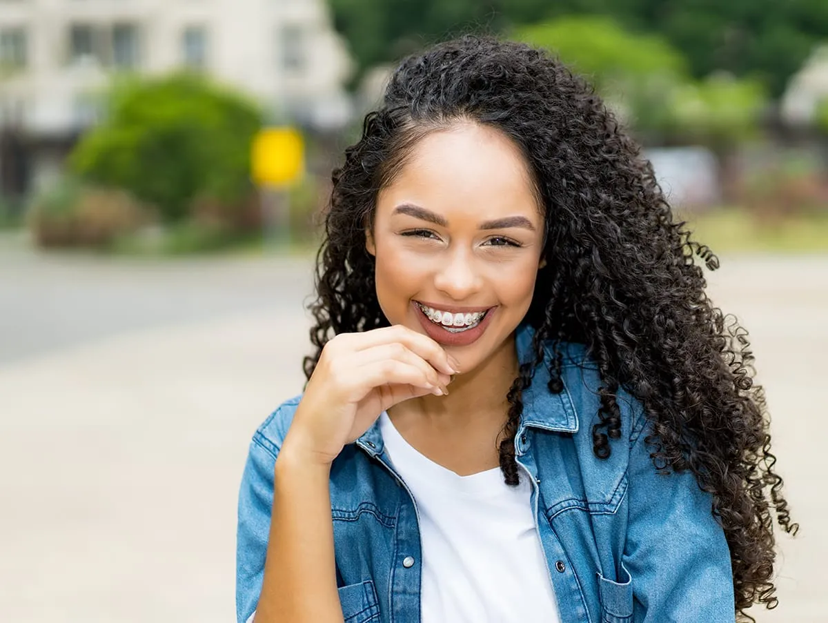 Pretty brazilian young adult woman with retainer outdoor in summer in city